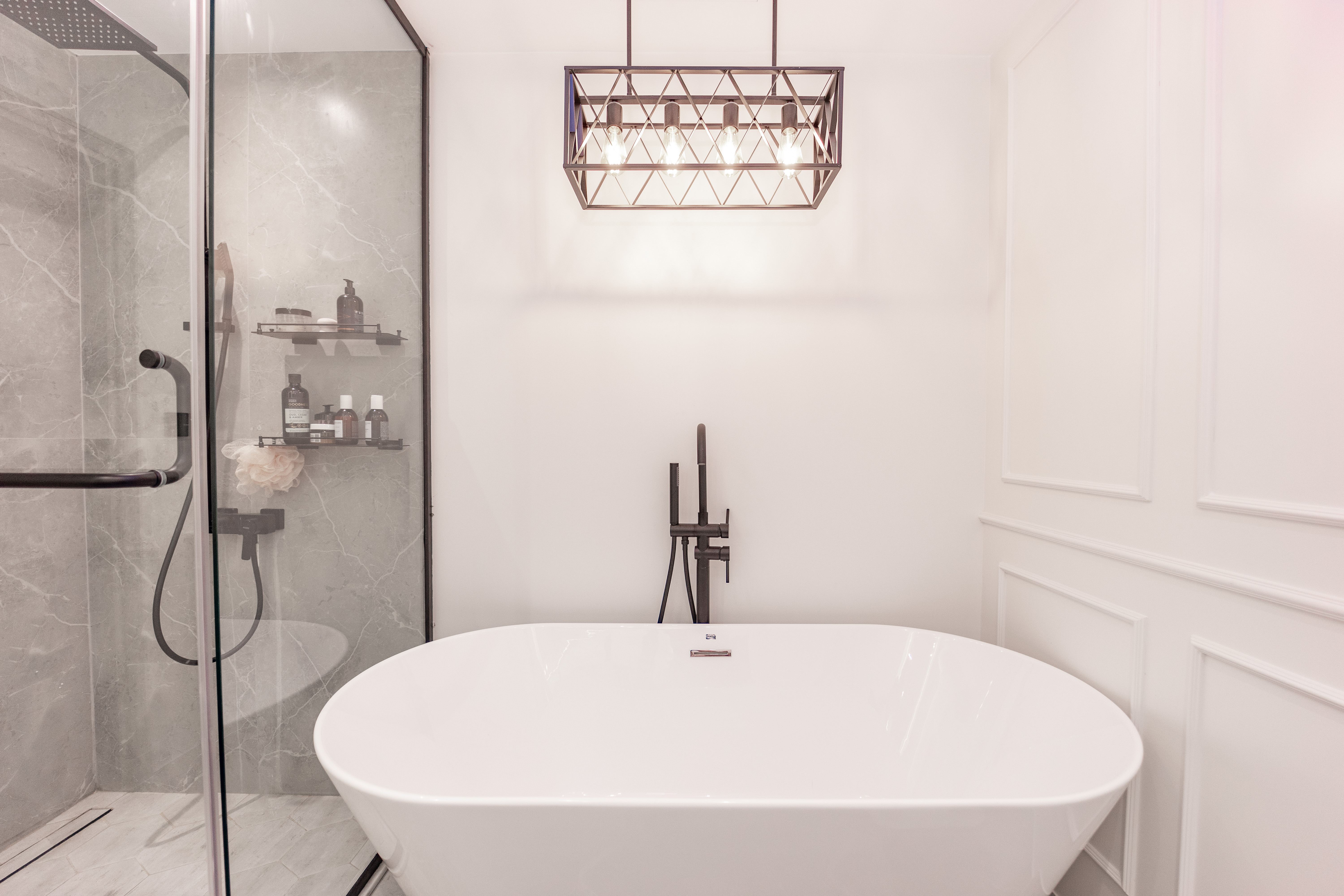 Elegant bathroom with freestanding white bathtub and geometric chandelier
