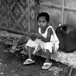 Kleines Kind hockt auf der Straße in einem Armutsviertel