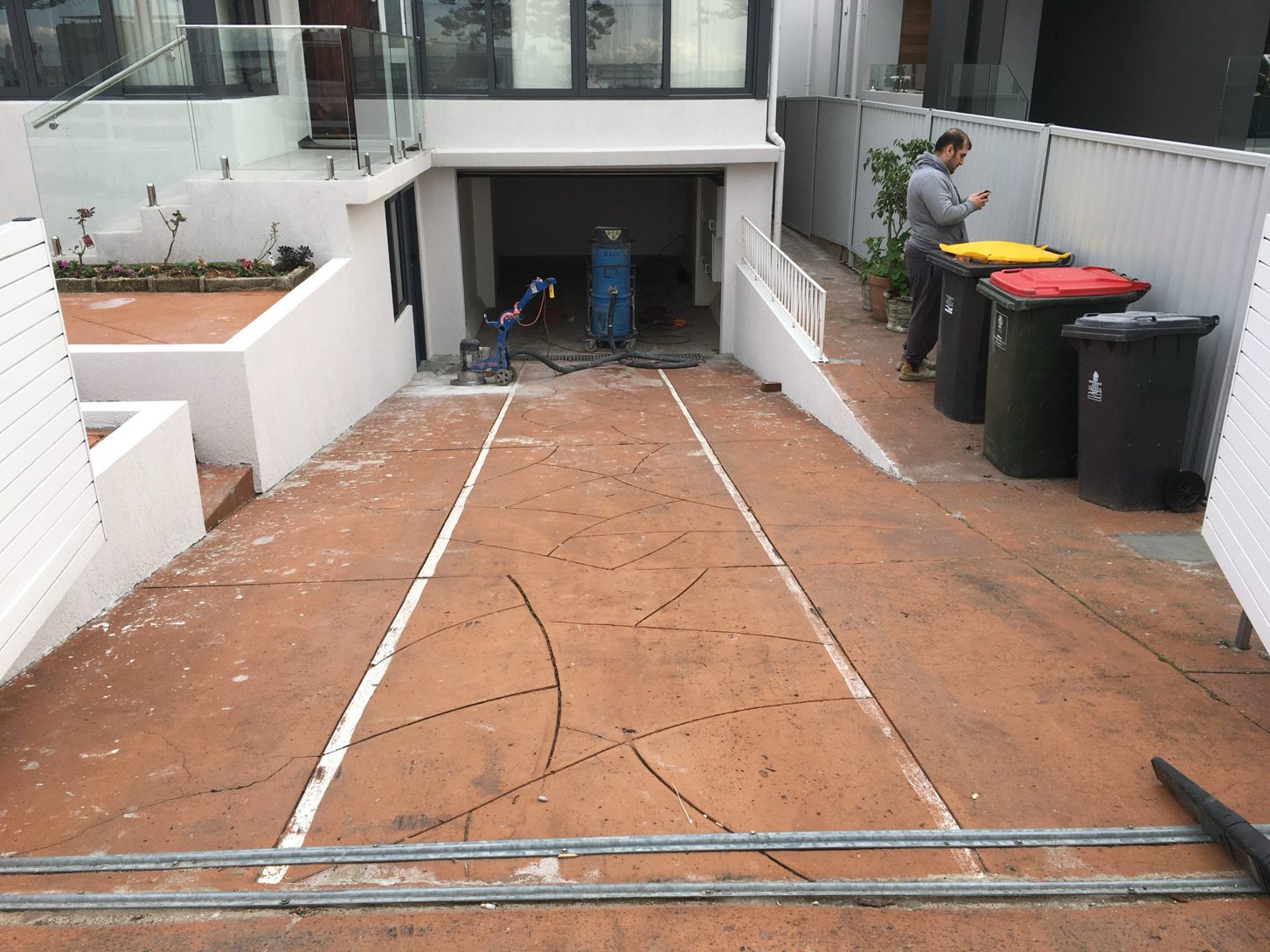 Old terracotta-toned concrete driveway being ground back and prepared before Spray Crete resurfacing