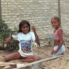 Zwei Mädchen sitzen lachend im Sand