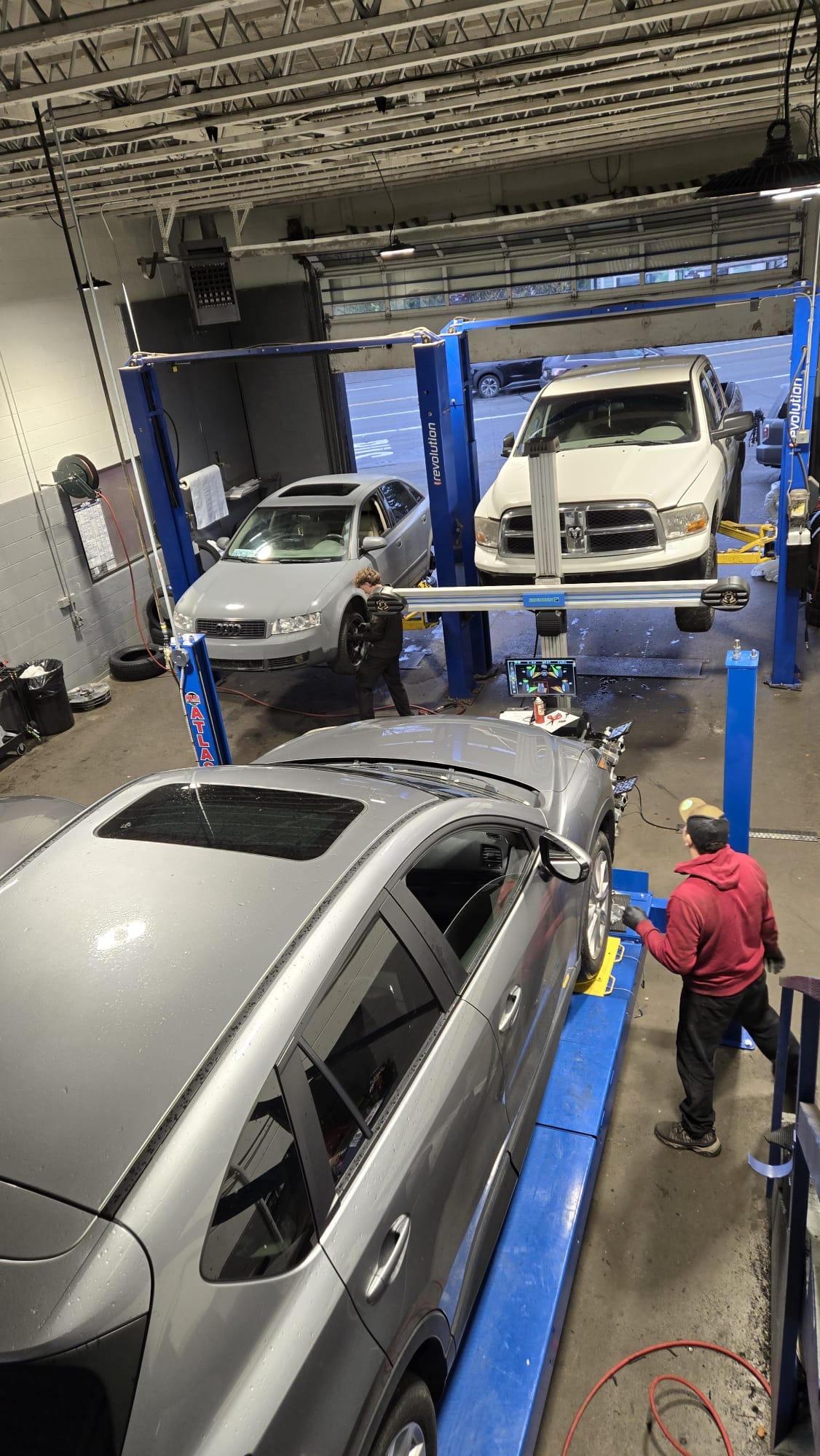 Three cars on lifts with mechanics working in the shop