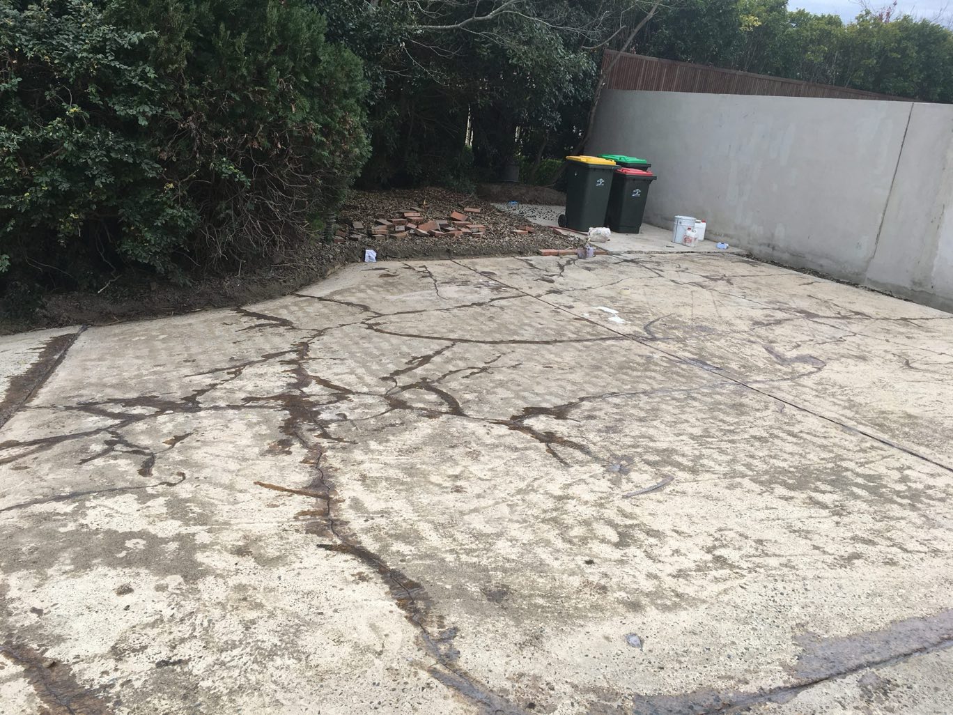 Old backyard concrete slab with heavy cracking and staining before Spray Crete resurfacing