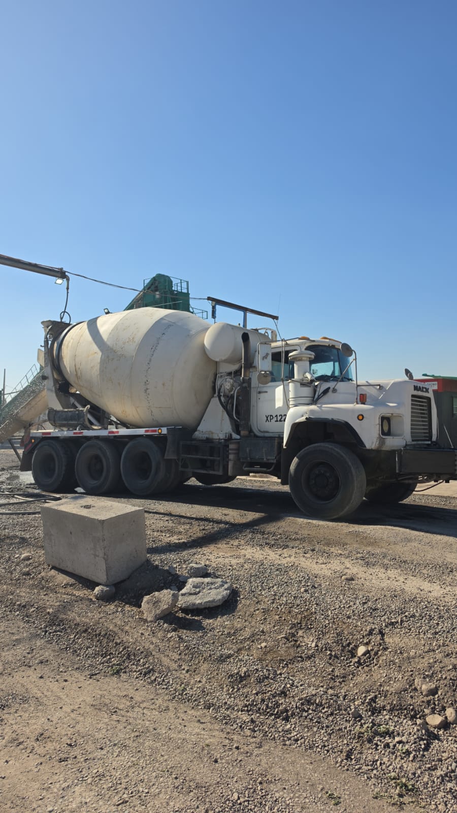 Camión mixer XP-122 cargando hormigón en planta con estructura verde