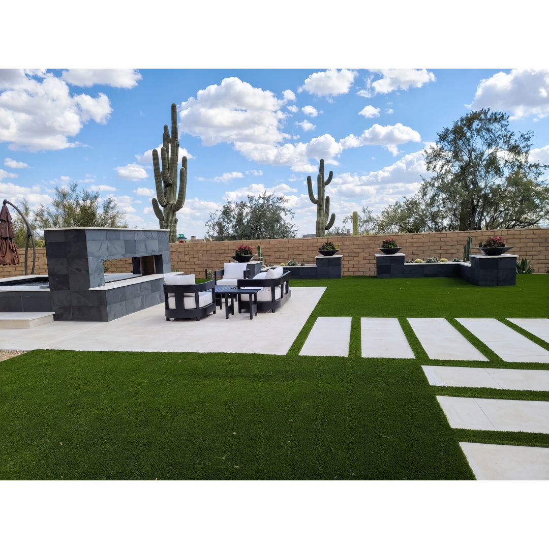 Desert backyard with linear stone pavers set into turf, a tile outdoor fireplace lounge, hot tub, and saguaro cacti