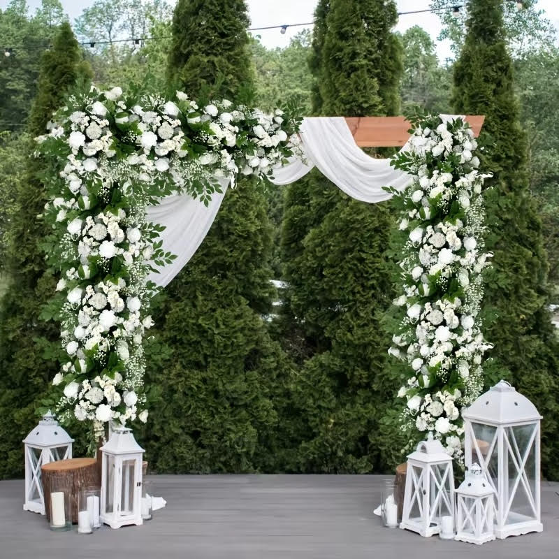 White outdoor wedding arch with greenery