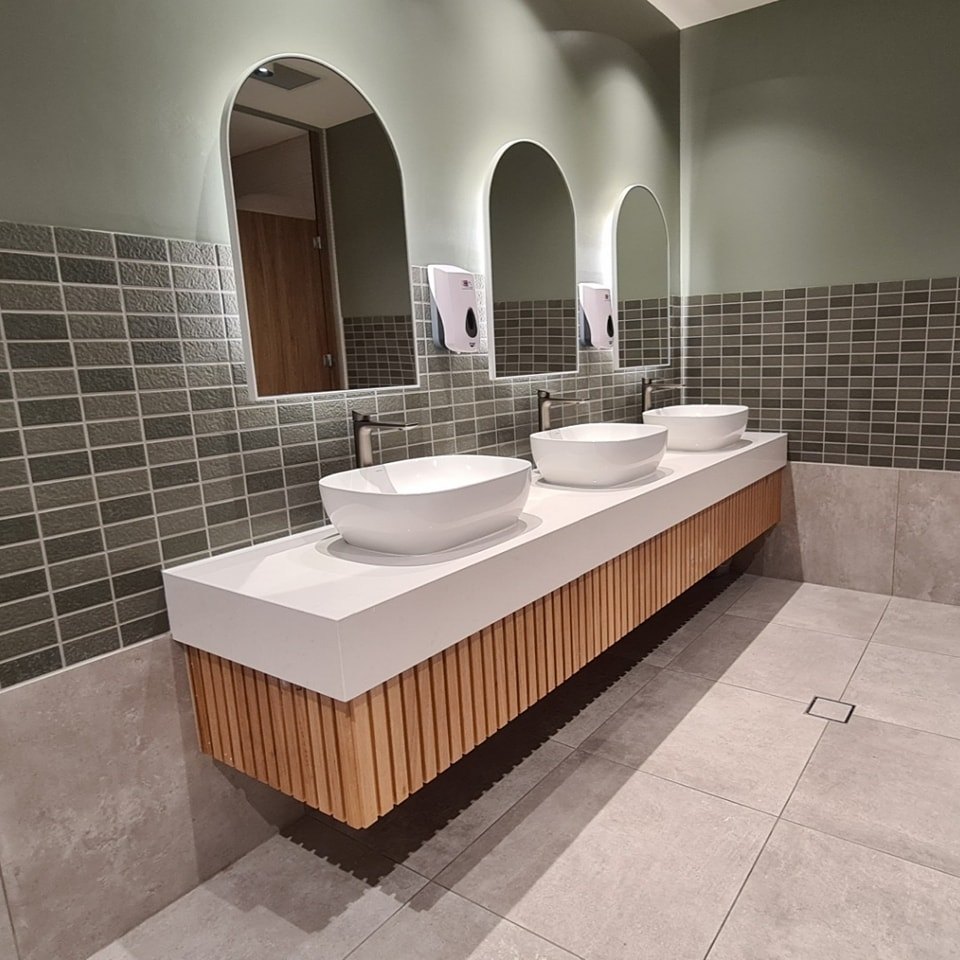 Double bathroom vanity with white vessel basins and arched mirrors