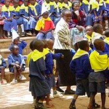 Lehrer inmitten vieler Schulkinder in blauen Uniformen bei einer Schulveranstaltung