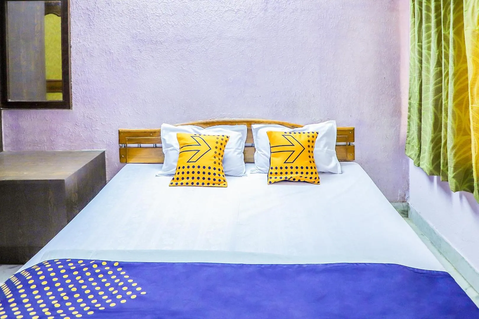 Classic Room with a crisp white double bed, yellow accent cushions, and a blue throw