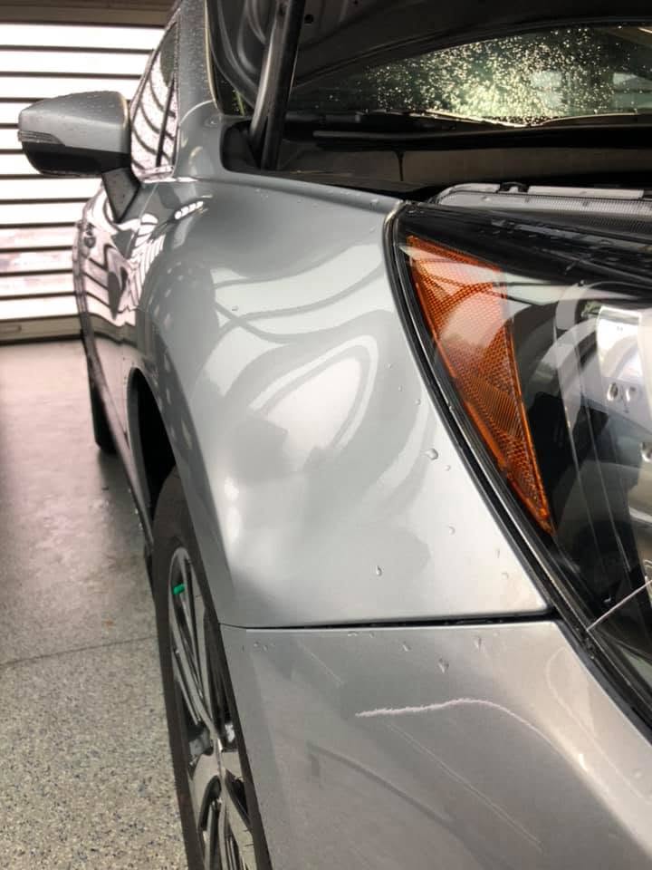 Silver SUV with hail dents on the fender before repair