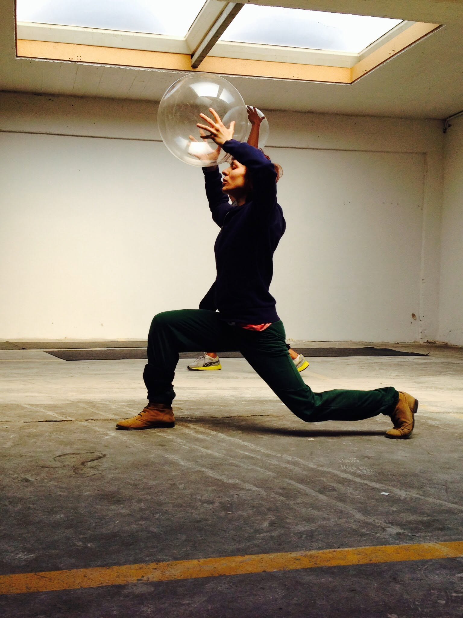 Dancer in a deep lunge, holding a large glass sphere overhead