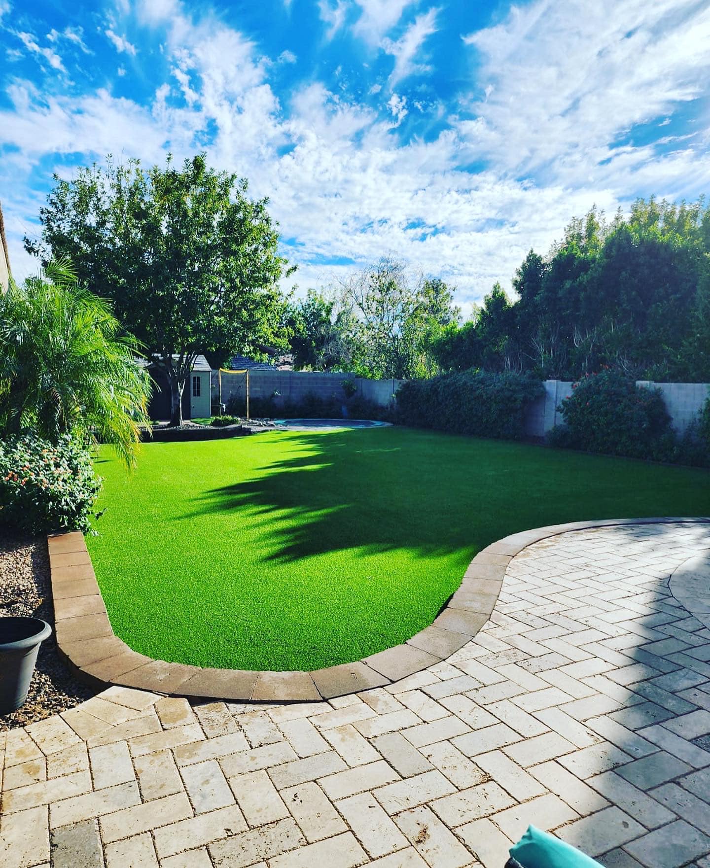 Poolside paver deck with geometric turf inlay at sunset
