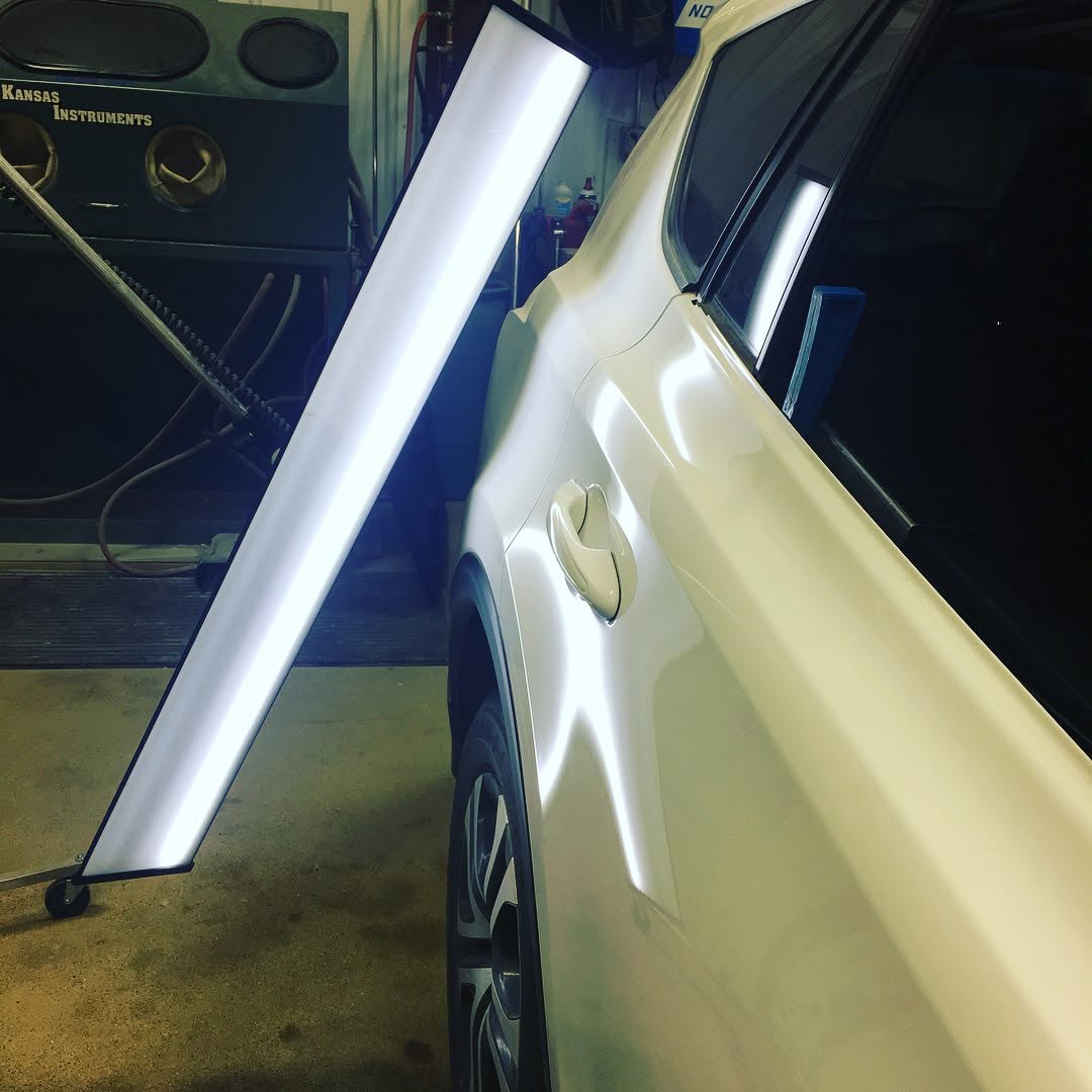 PDR reflection board lighting up a white vehicle door panel during repair