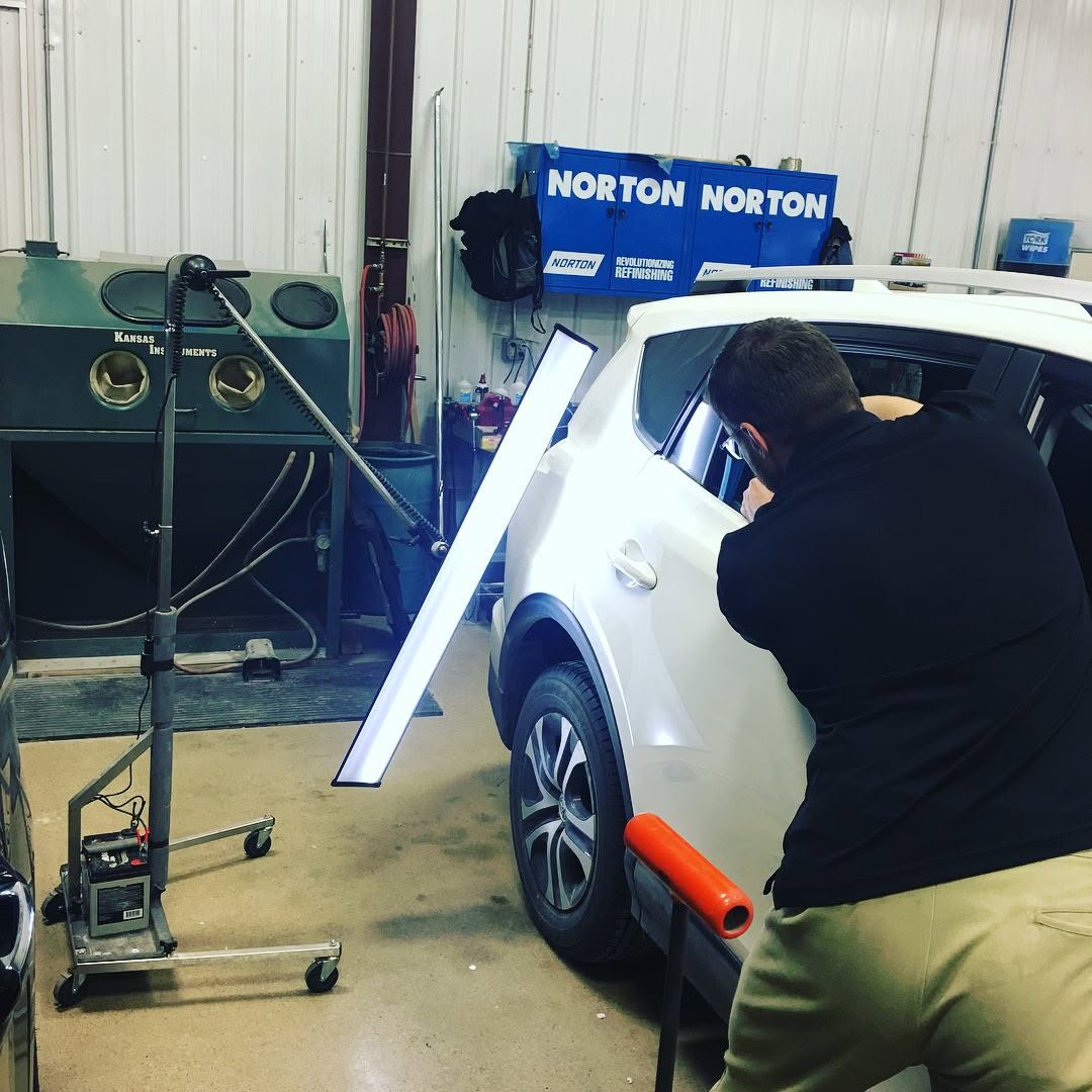 Dent Force PDR technician using a reflection board on a white vehicle door