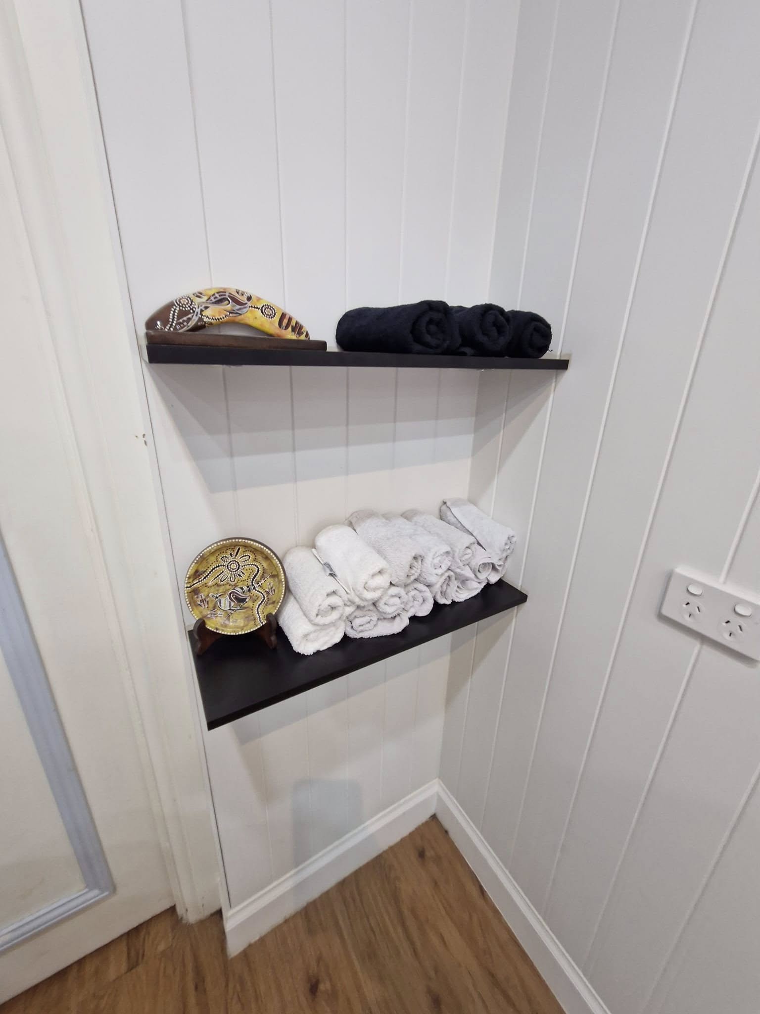 Custom floating dark shelves in bathroom with towel storage