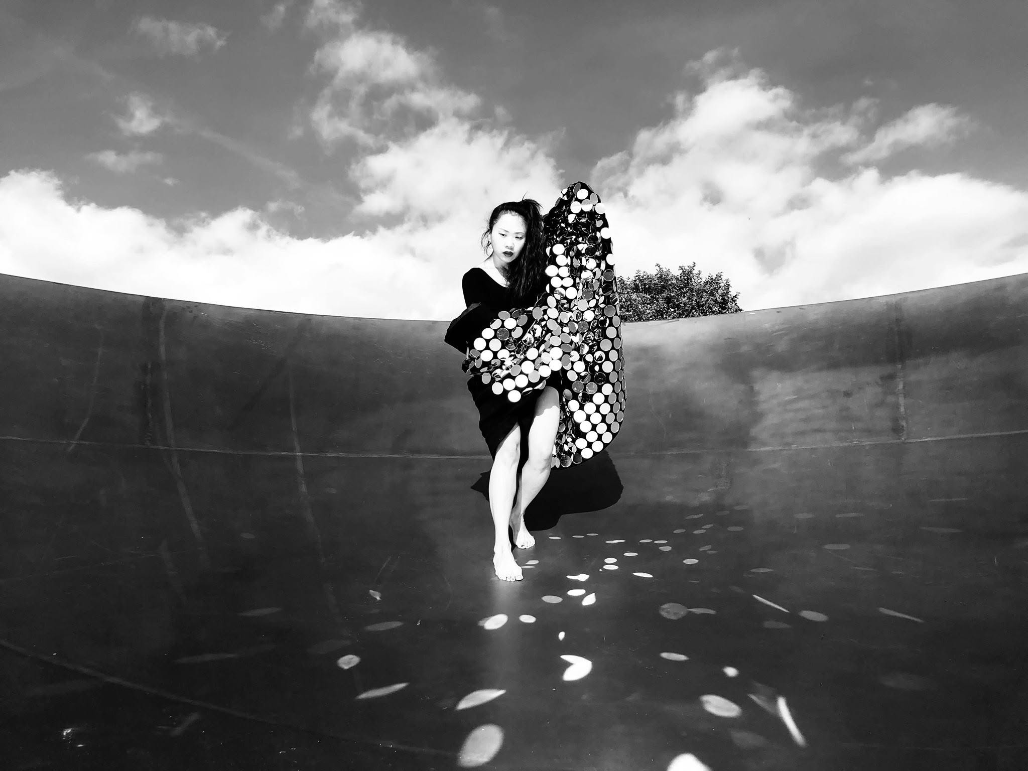 Solo performer with mirrored costume in a concrete bowl