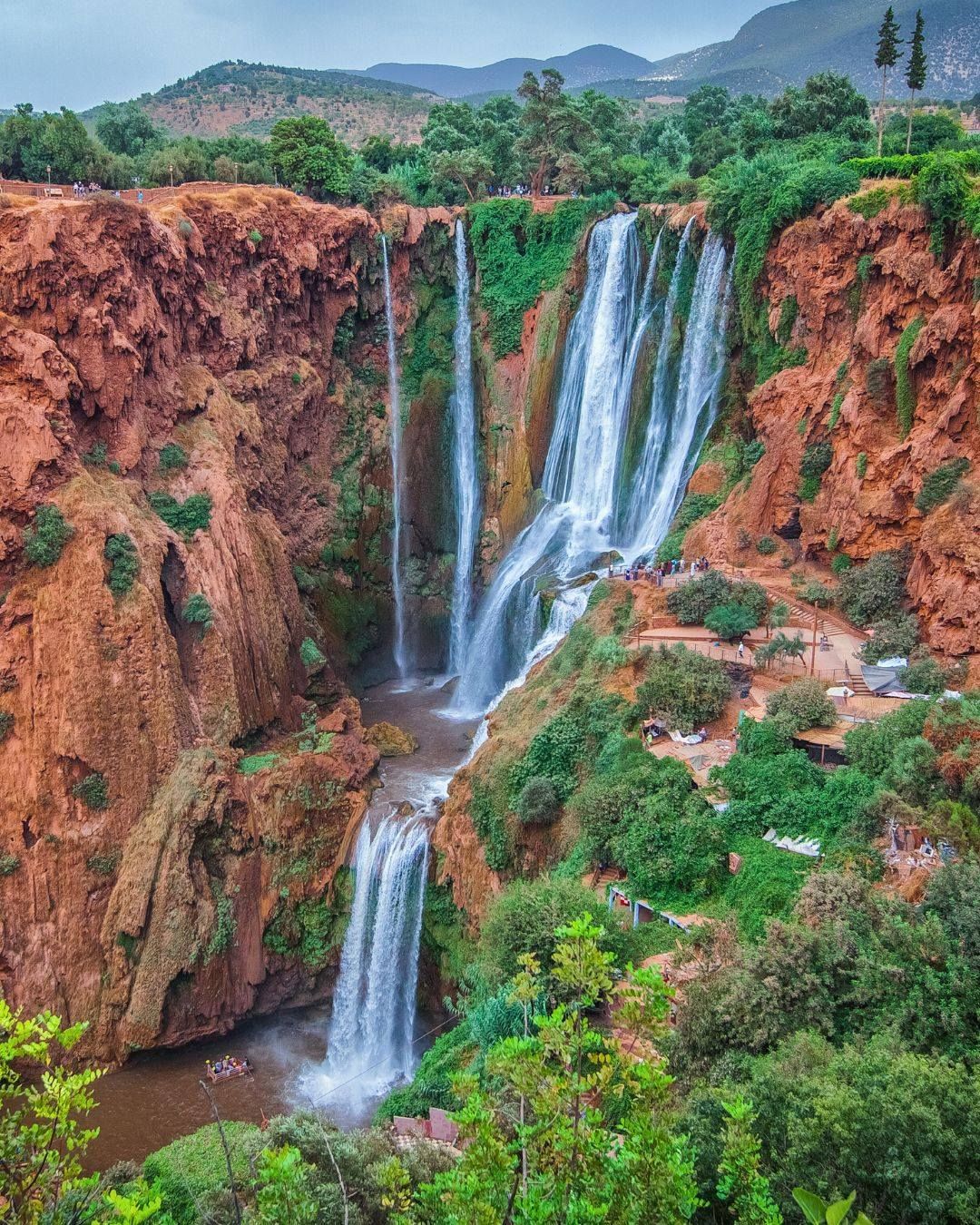 Ouzoud Waterfalls cascading down red cliffs with lush vegetation