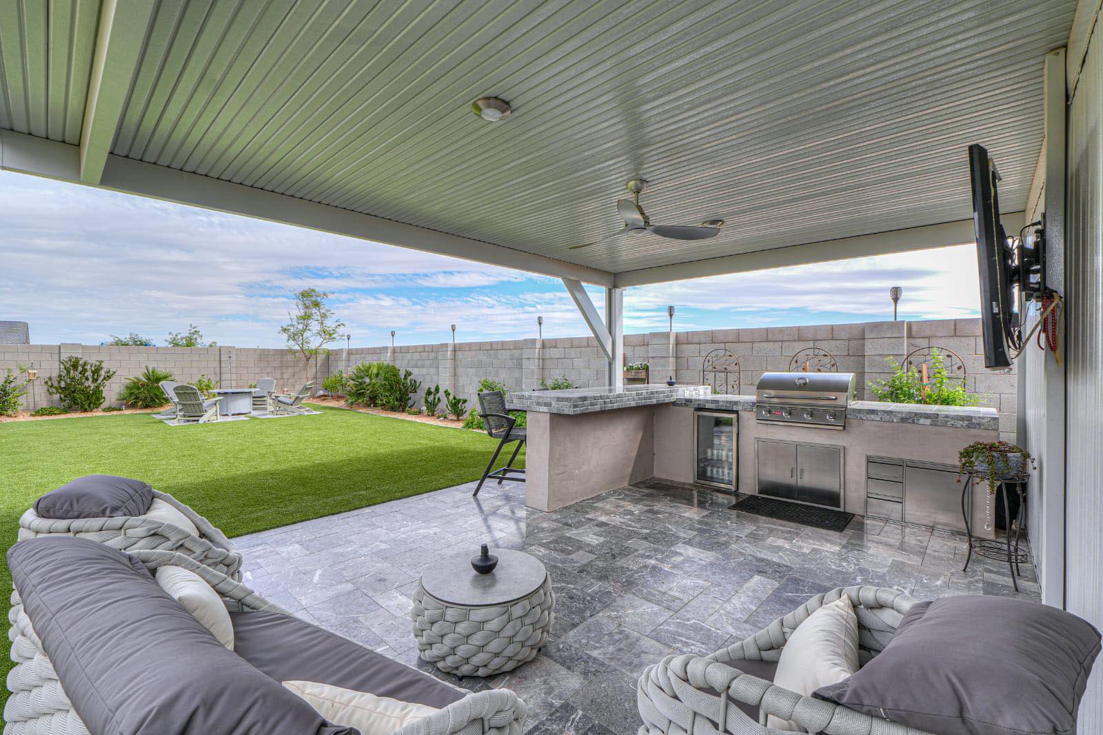 Backyard pool and paver patio bordered by lush turf