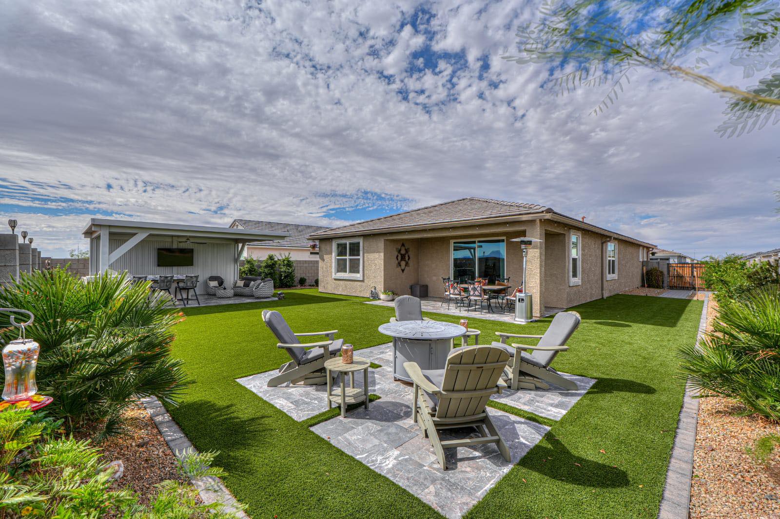 Spacious backyard turf lawn with fire pit seating and covered patio