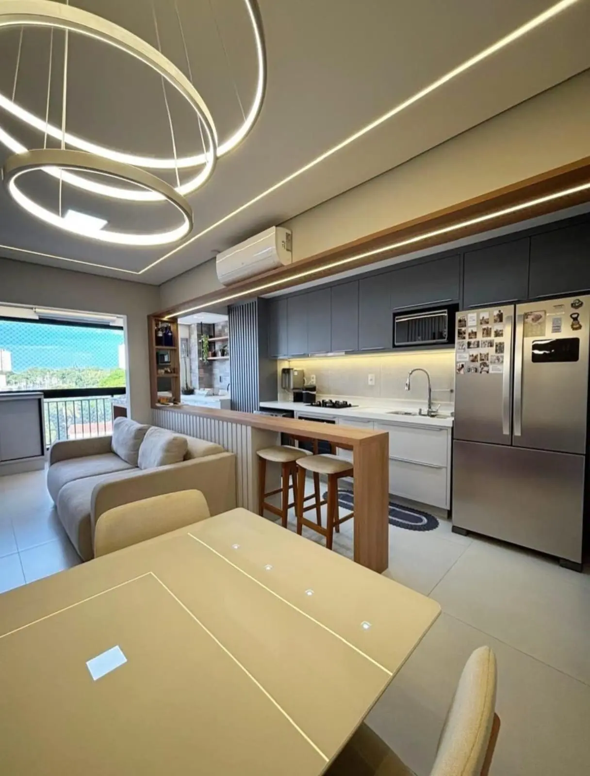 Sala integrada com cozinha, lustre circular LED e armários cinza