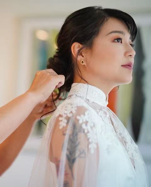 Bride in white lace qipao with elegant updo being prepared