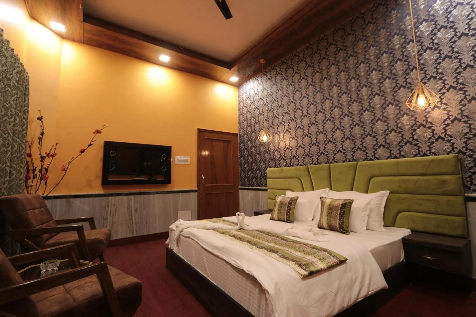 Superior Room with a green velvet headboard, damask wallpaper, pendant lights, and lounge chairs