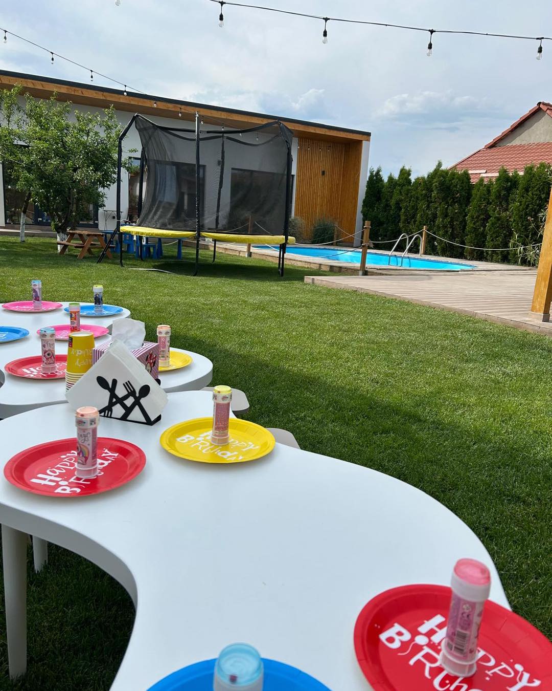 Masă decorată pentru petrecere aniversară în grădina cu piscina și trambulina