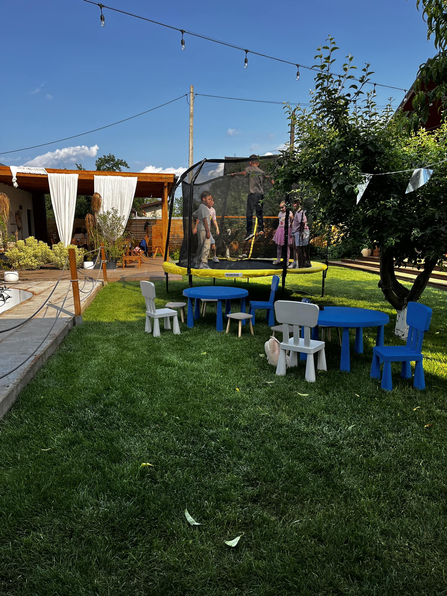 Copii la joacă pe leagăne și tobogan în grădina Kids Club