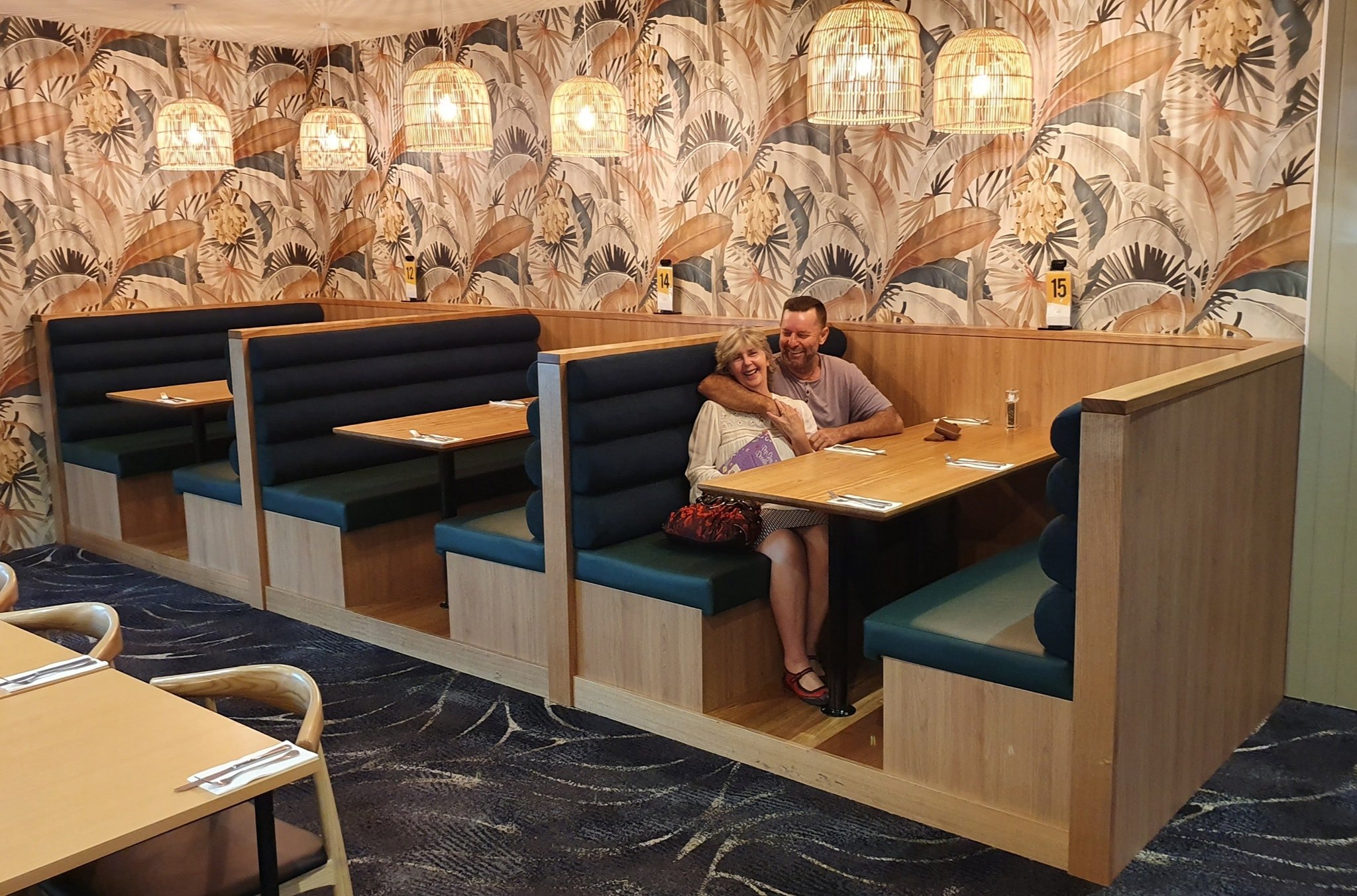 The Benson family sitting proudly in a completed commercial restaurant booth seating fitout — their own handiwork