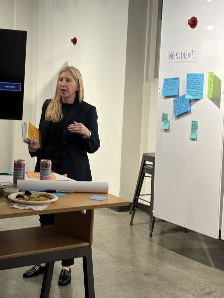 Facilitator standing near whiteboard with "INGREDIENTS" and participant notes