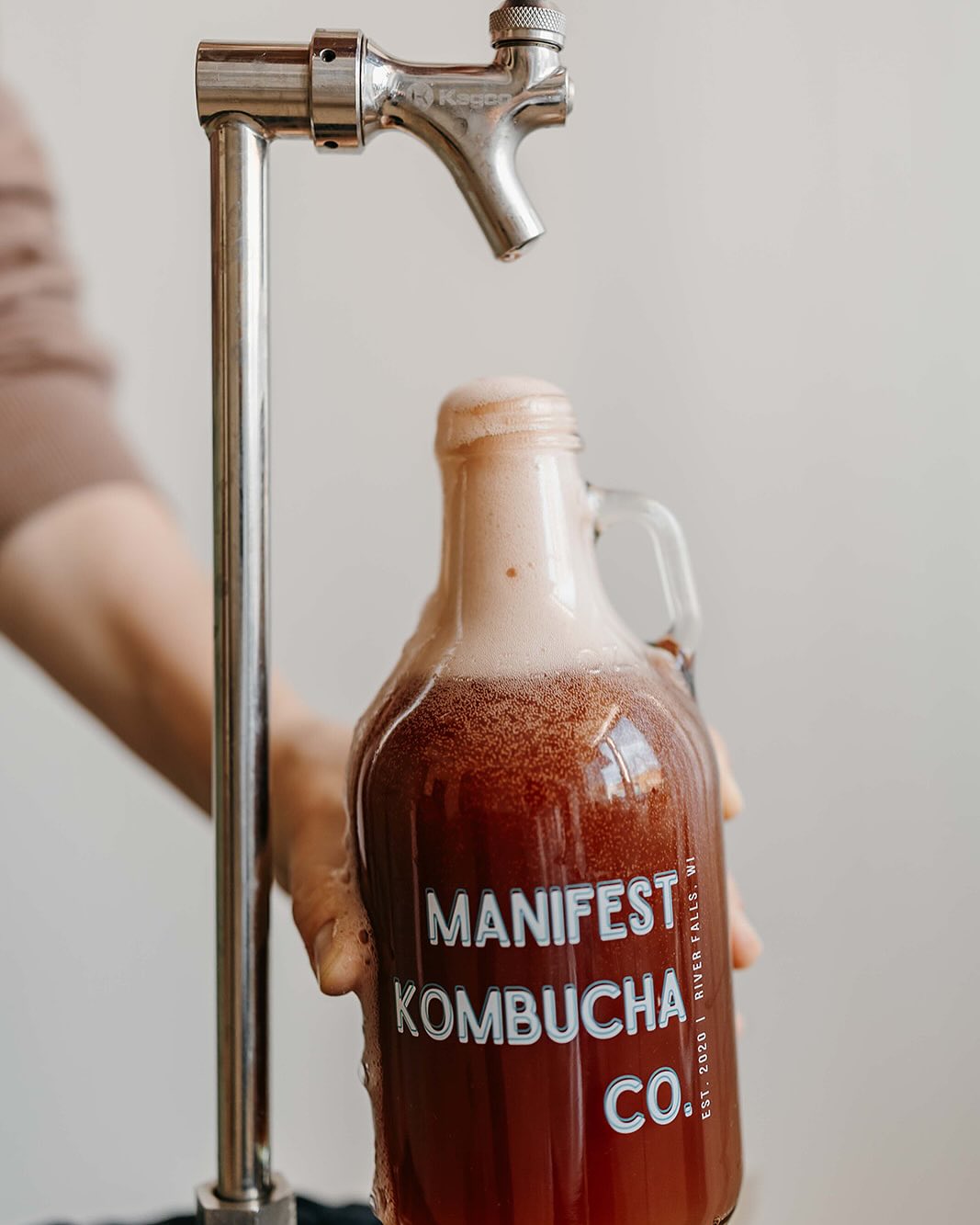 Fresh kombucha being poured from tap
