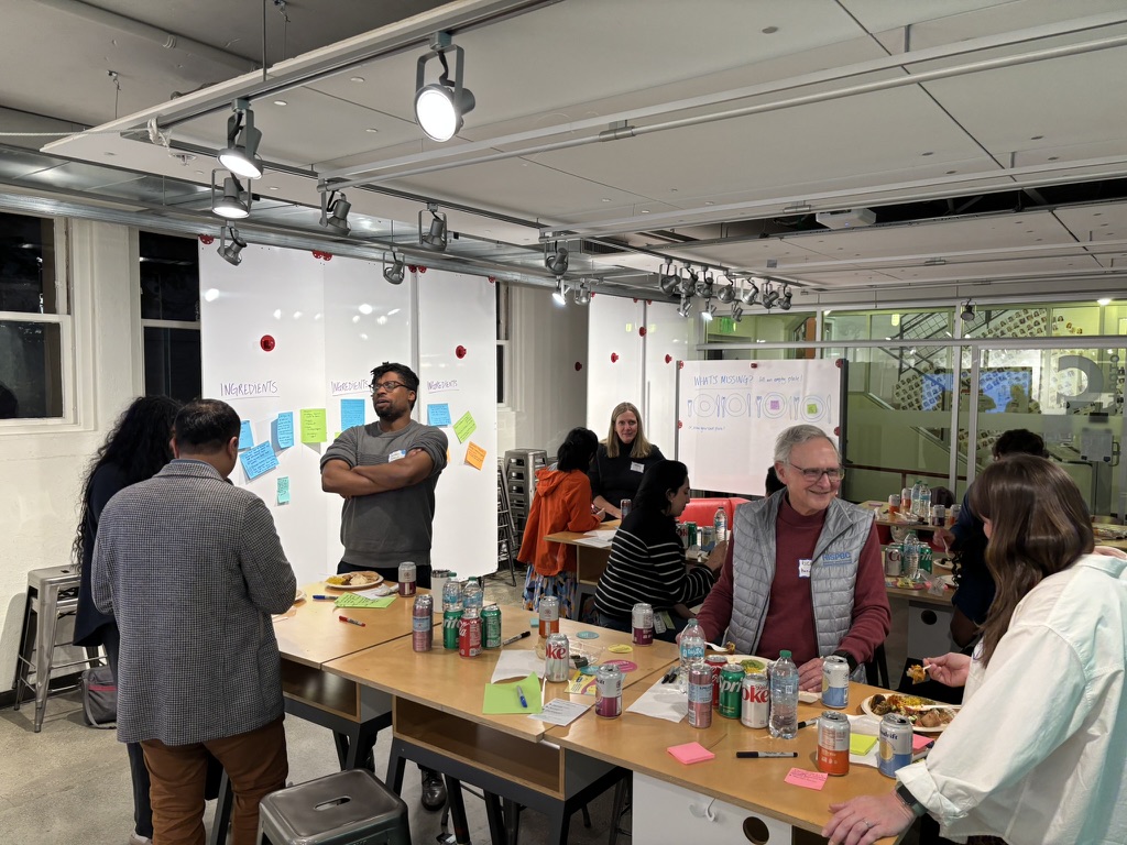 Participants engaged in discussion at R&Dinner event at Stanford d.school