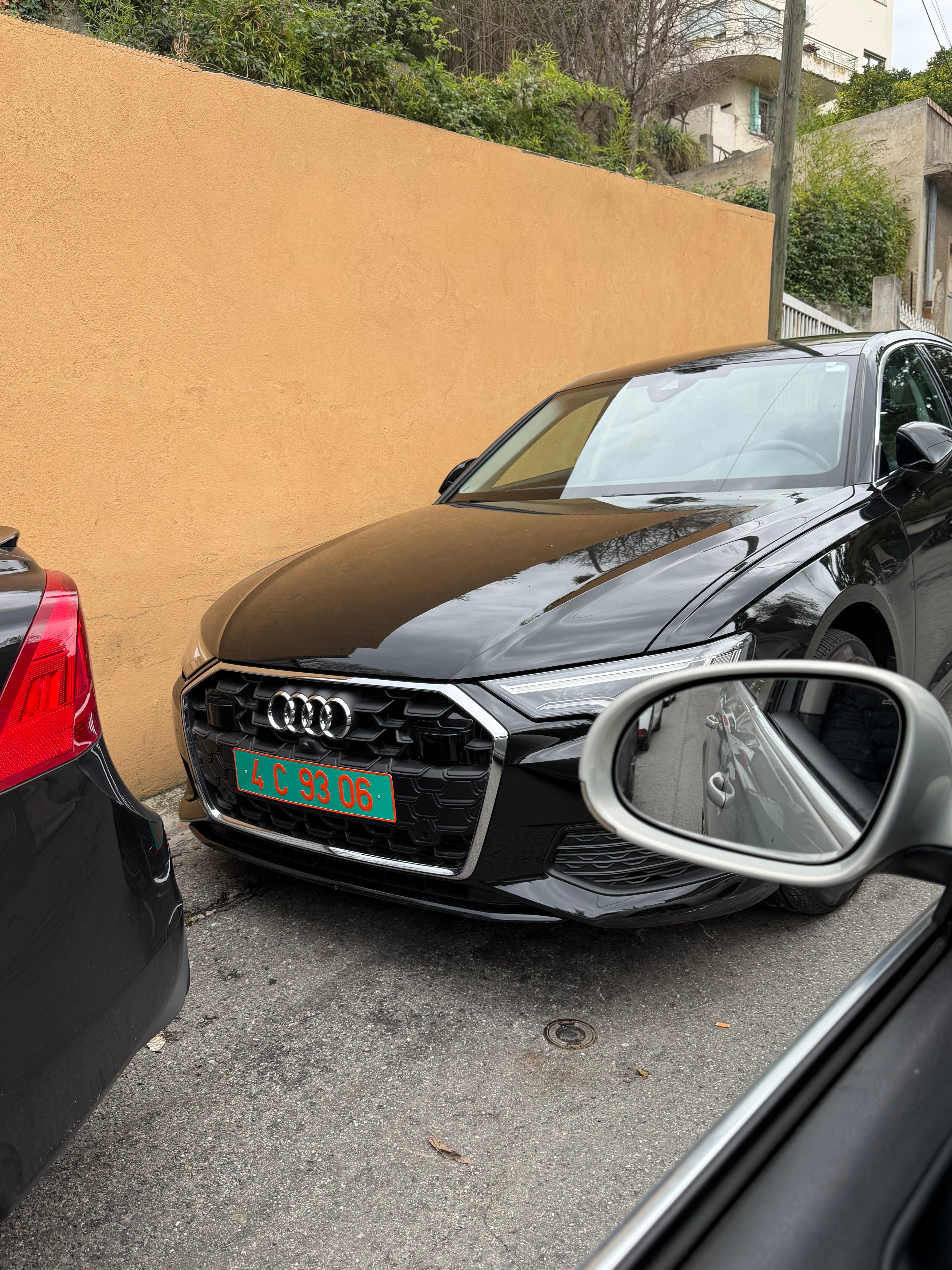 Plaque consulaire verte 4 C 93 06 sur une Audi A6 noire garée contre un mur ocre — code 4 Algérie, consulat émis par la préfecture de Seine-Saint-Denis (93), numéro de série 06