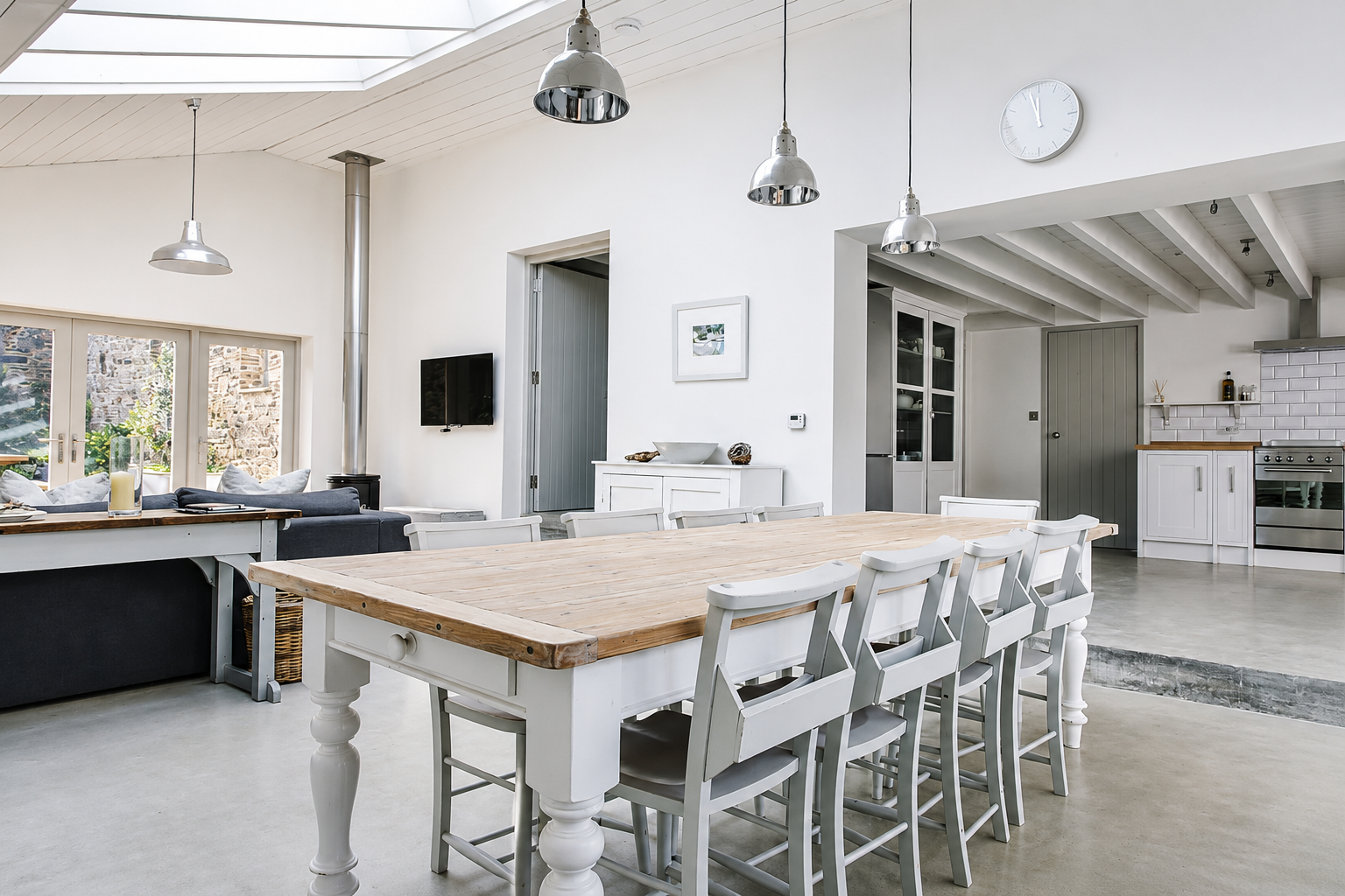 Bright open-plan kitchen and dining room with farmhouse table and industrial pendant lights