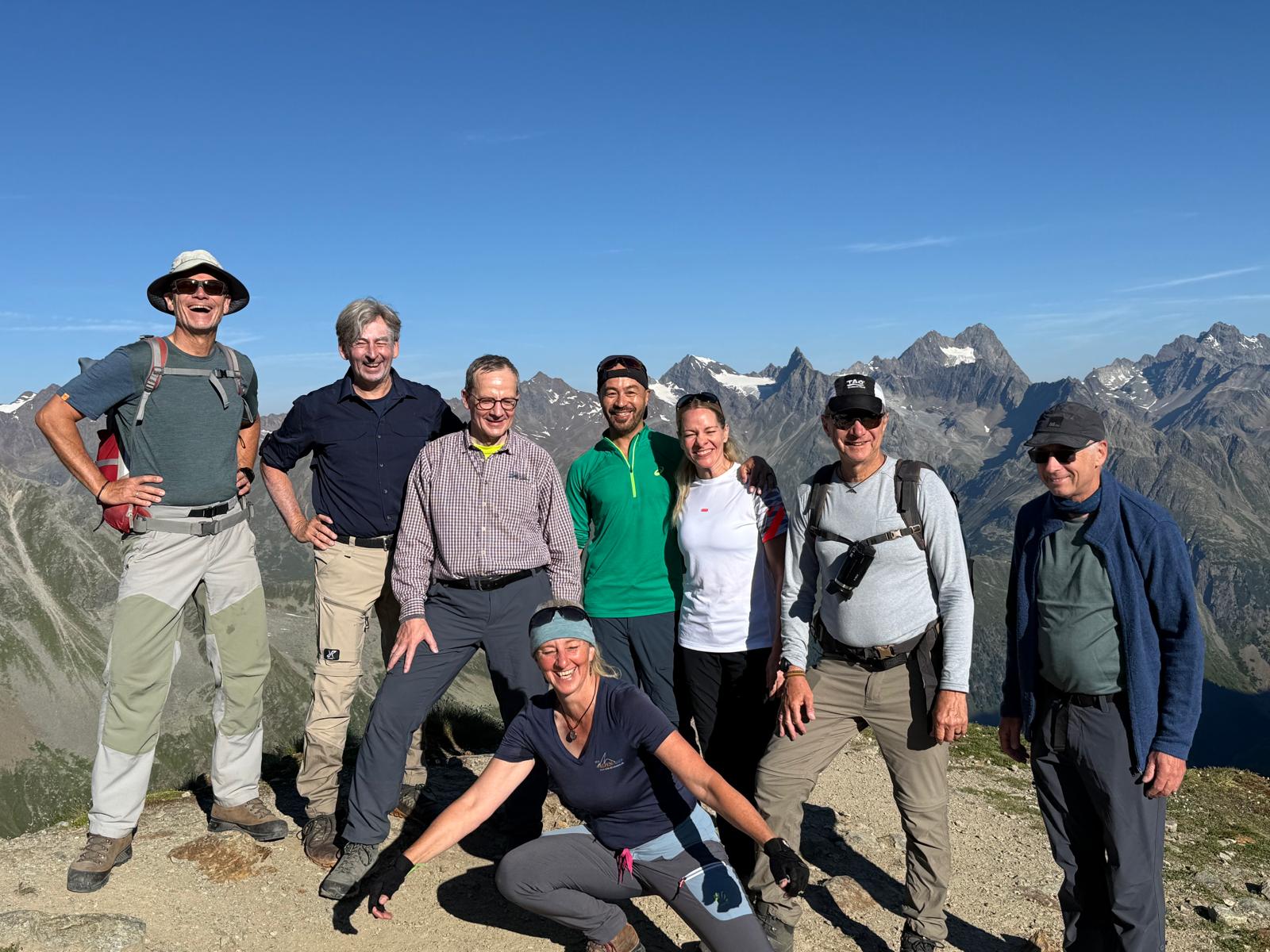 Gruppe der 100Plus Community an einem Tisch vor einer Alm in den Bergen