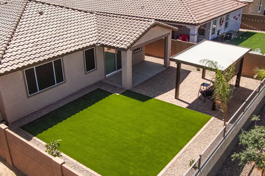 Aerial view of backyard with white patio cover, pavers, and string lights