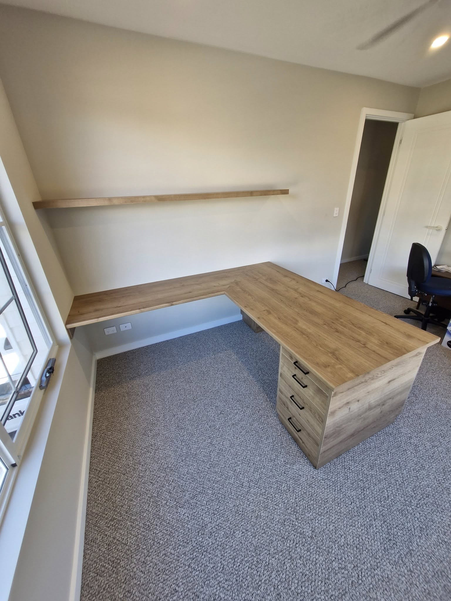 Custom L-shaped timber desk with floating shelf for home office