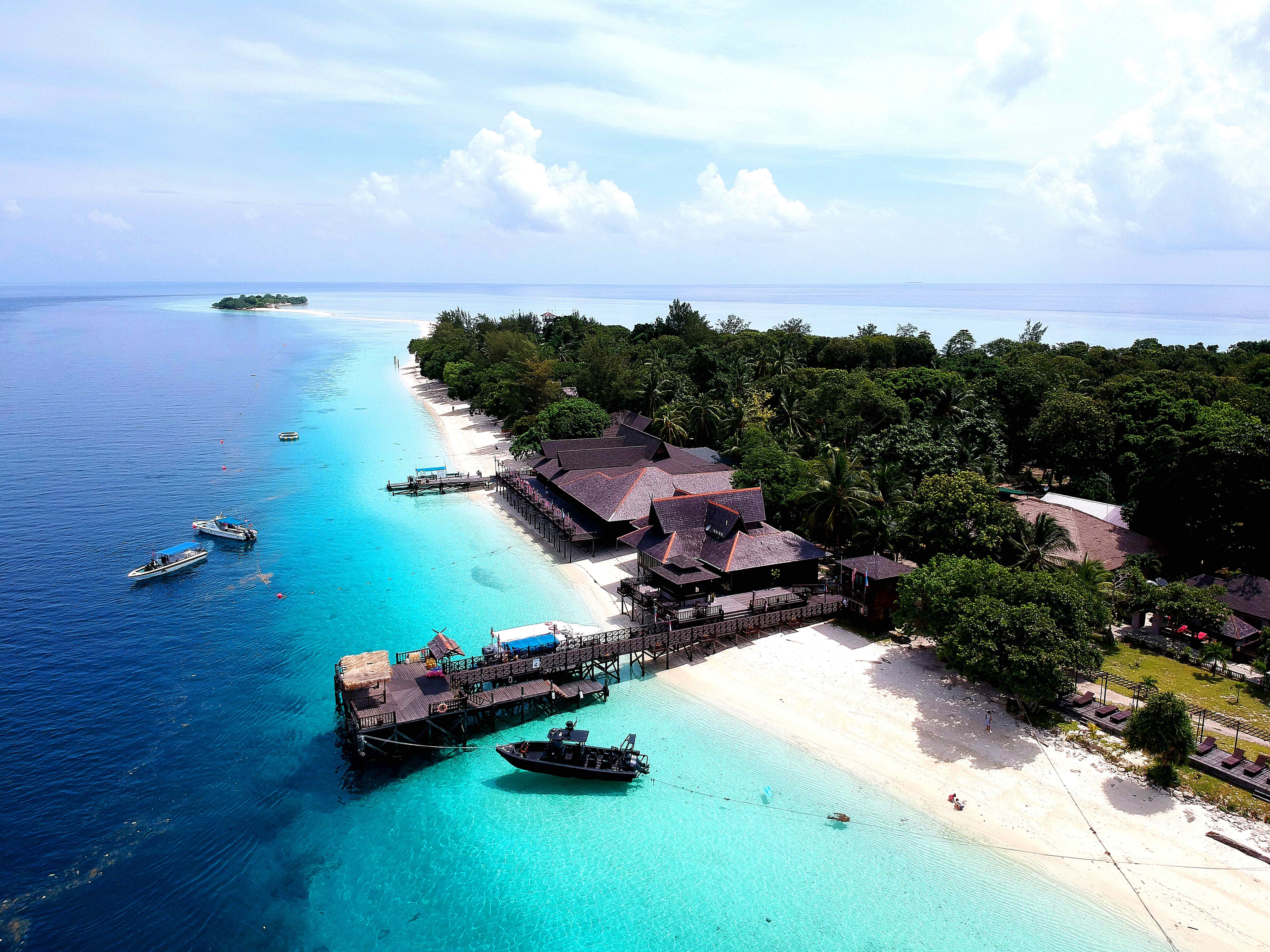 Aerial view of Mataking Island Sabah with white sand beach, dive resort jetty, and turquoise waters, Malaysia