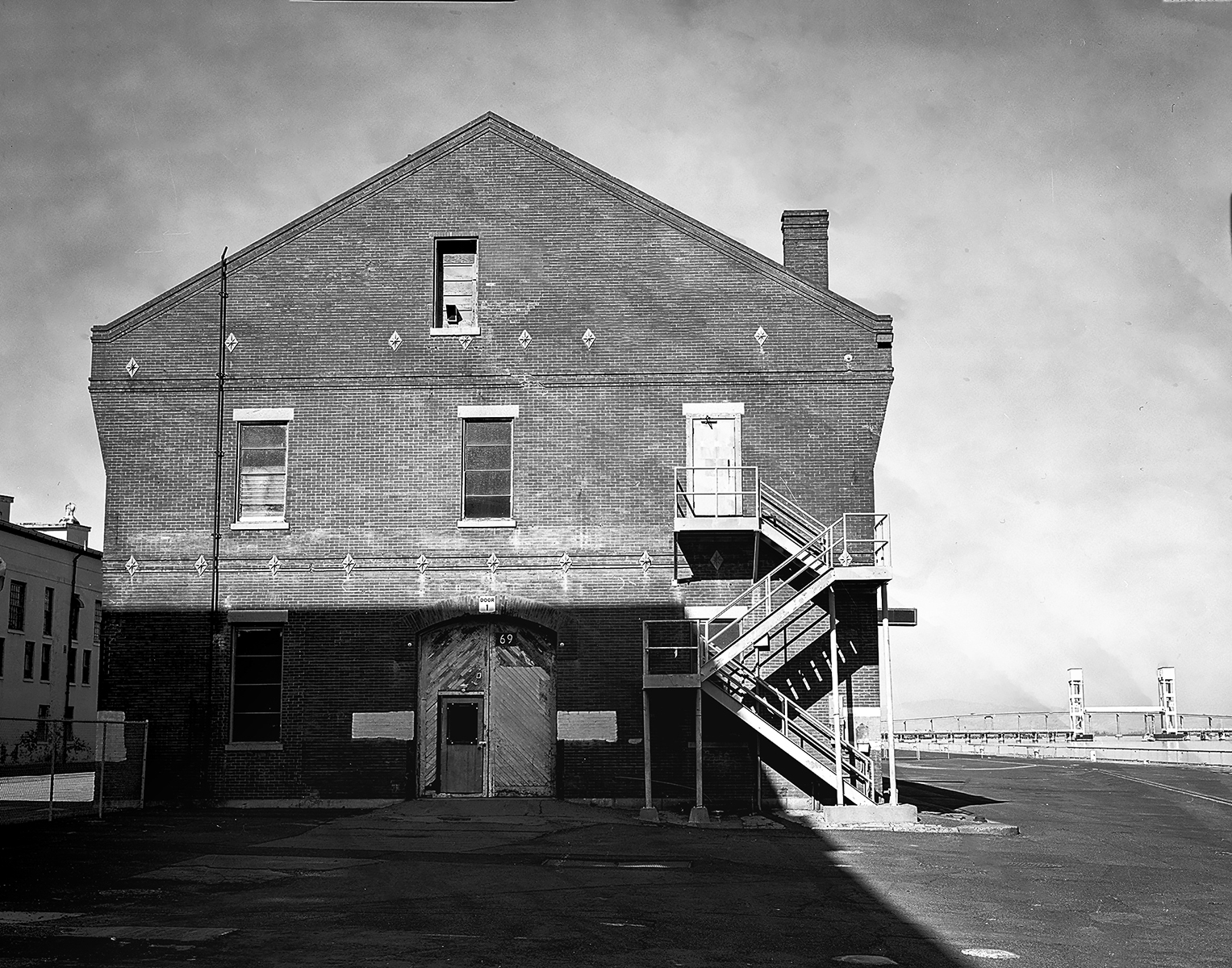 Historic brick industrial warehouse building numbered 69 with external metal staircase at waterfront shipyard