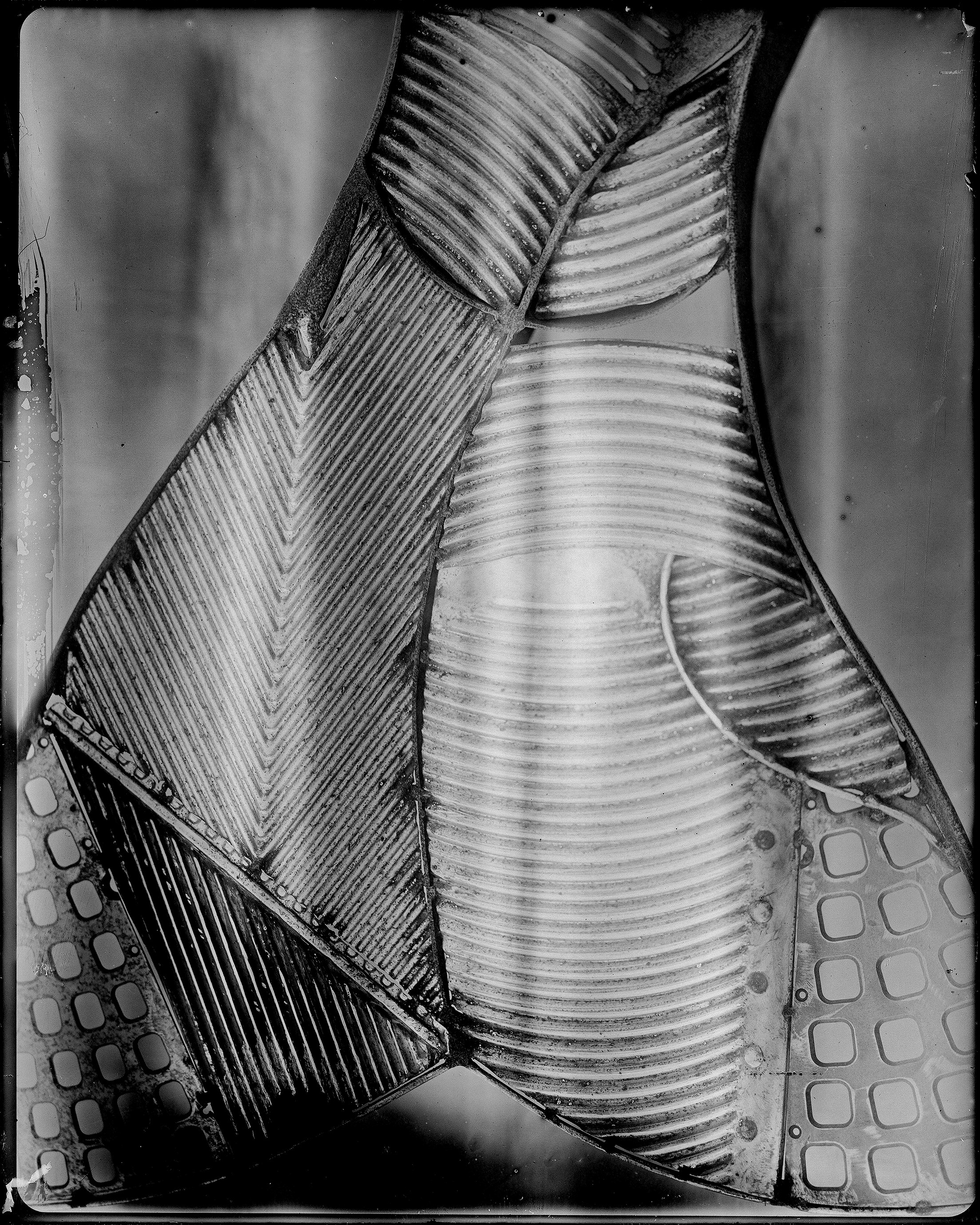 Abstract close-up of medieval armor with intricate ribbed curved sections and chevron herringbone patterned panels showing wet plate collodion edge artifacts