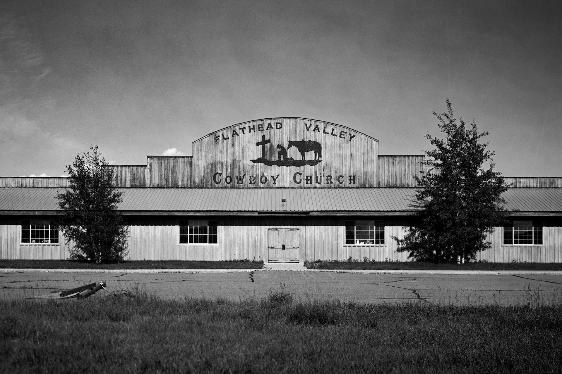 Flathead Valley Cowboy Church wide rustic wooden building with iconic praying cowboy and horse silhouette sign