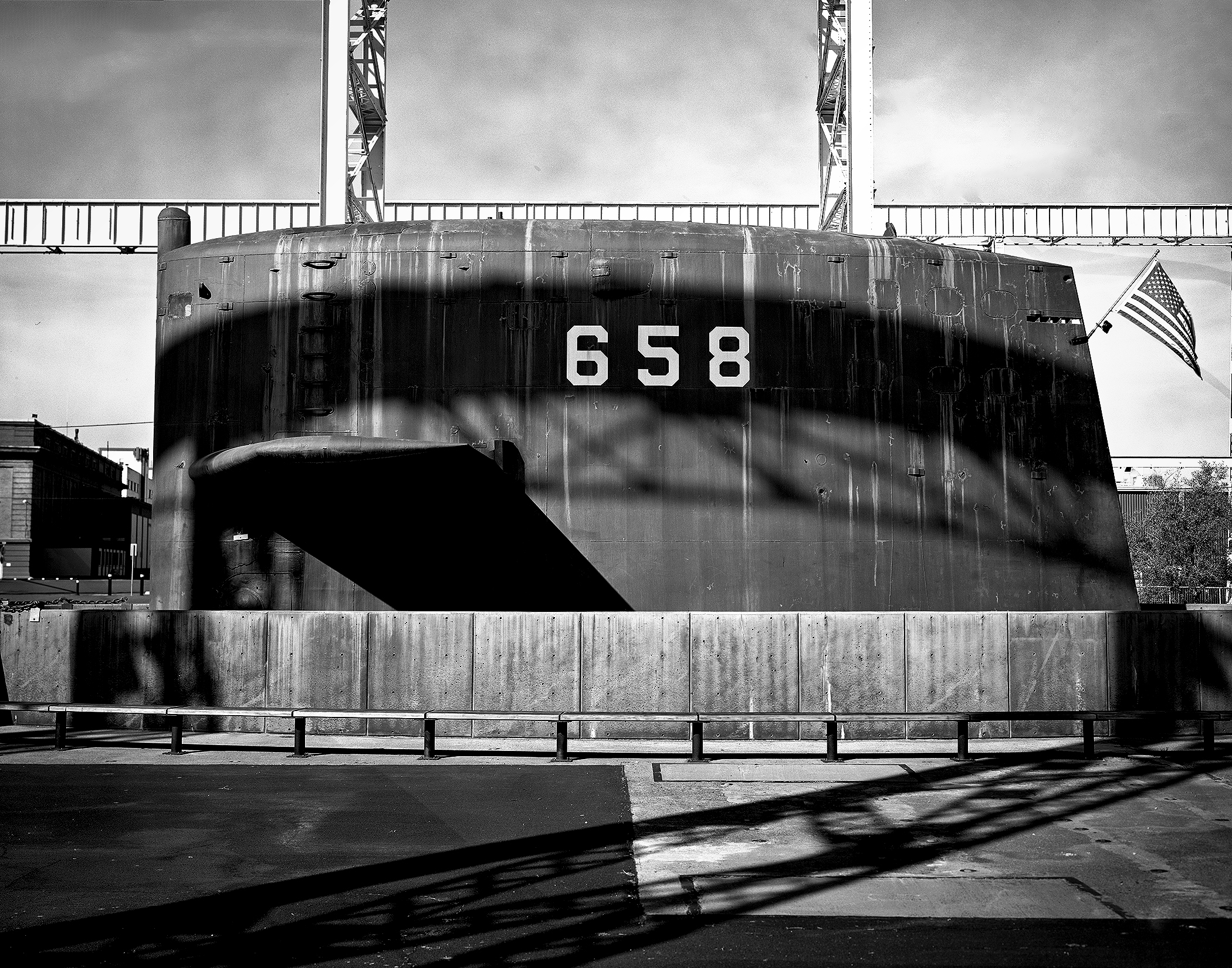 Submarine 658 bow section close-up frontal view with American flag and dramatic crane structure shadows