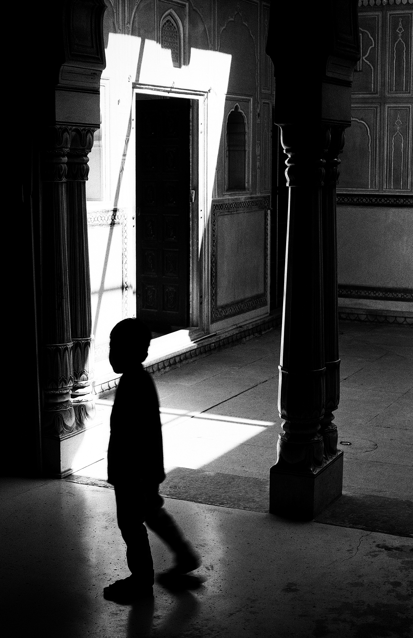 Silhouetted child walking through ornate palace interior with dramatic light streaming through doorway