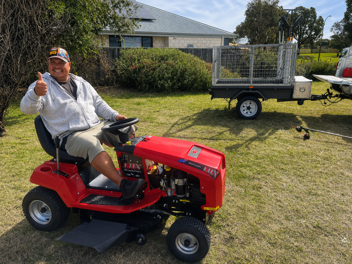 Participant on a ride-on lawn mower giving a thumbs up, showing independence and skill building