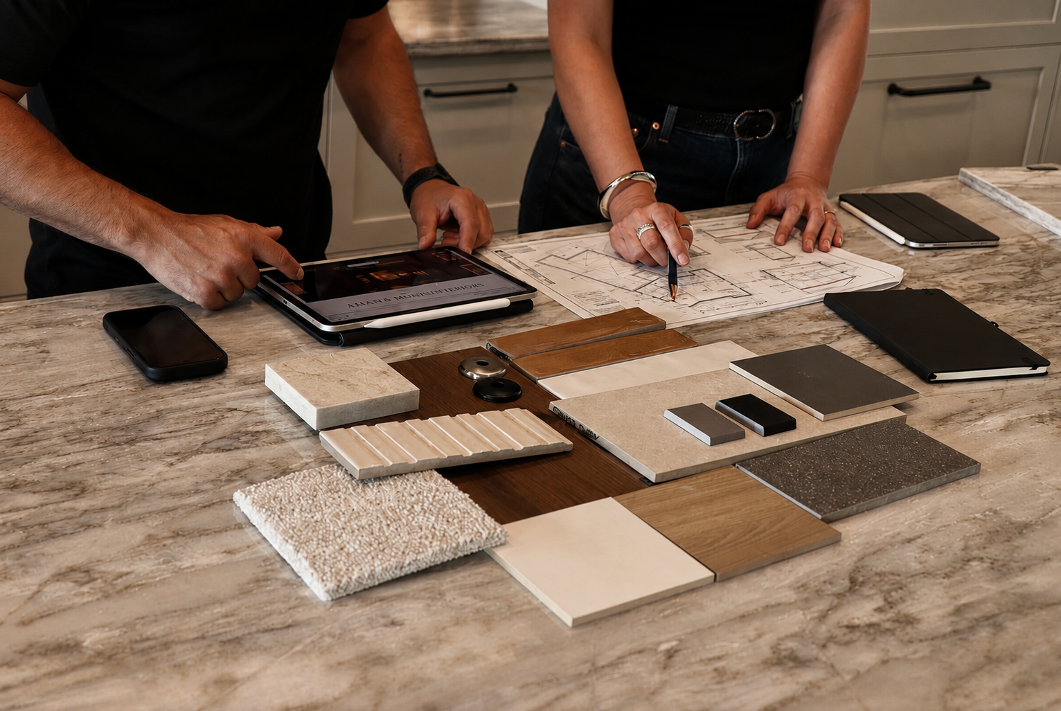 Builder and client reviewing floor plans and material selections on a marble kitchen island
