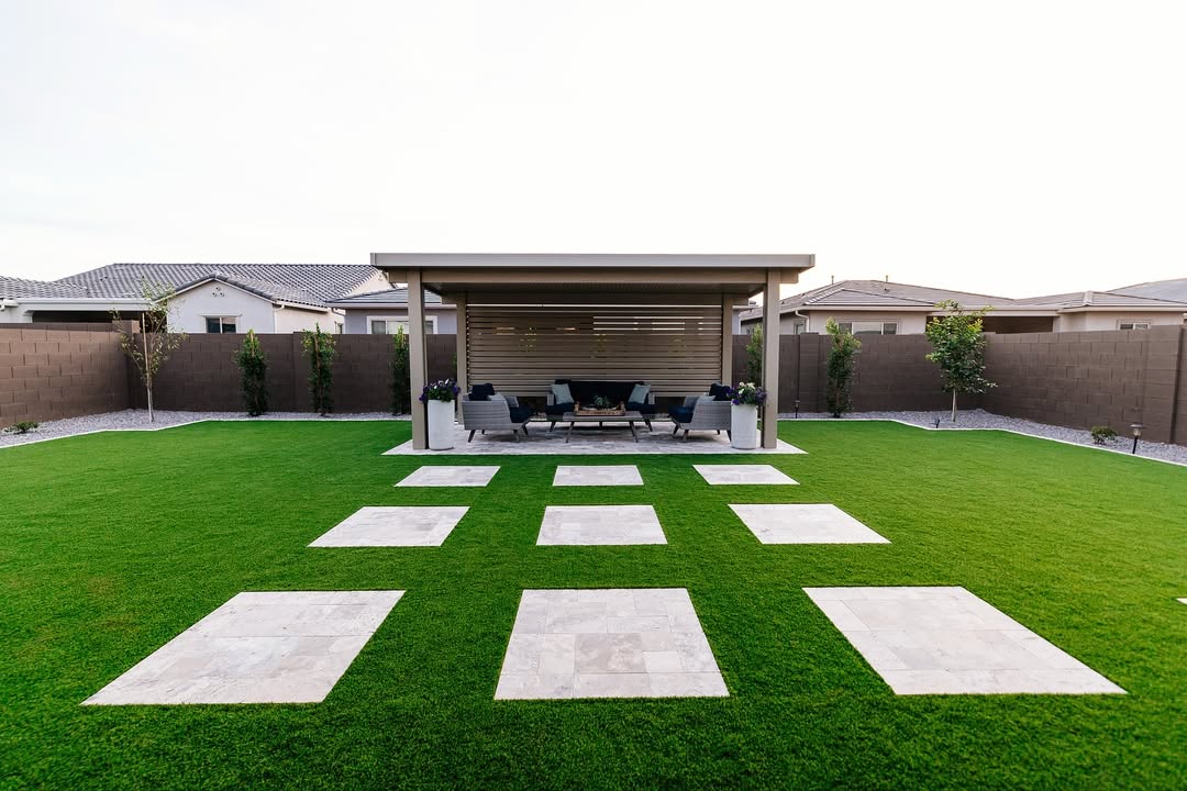 Symmetrical backyard with pergola seating, gravel borders, and 3x3 grid of travertine steppers in turf