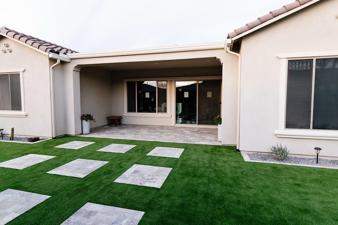 House patio cover with travertine stepping stones set in lush artificial turf lawn
