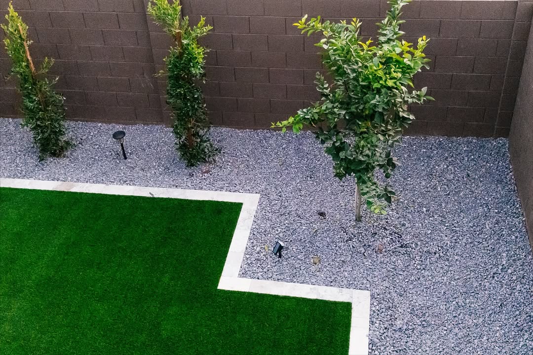 Overhead view of artificial turf corner with travertine border edging, trees, and gravel
