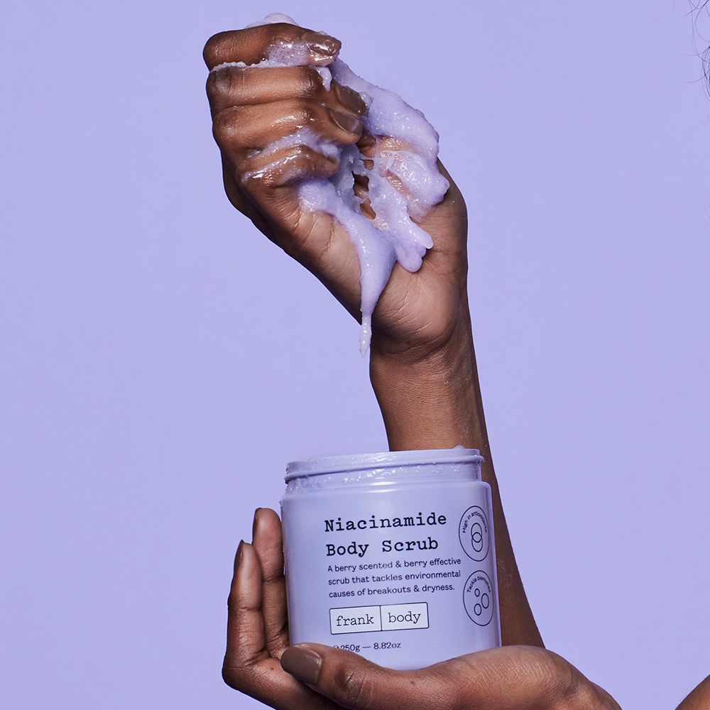 Frank Body Niacinamide Body Scrub pot tenu avec mousse dans la paume