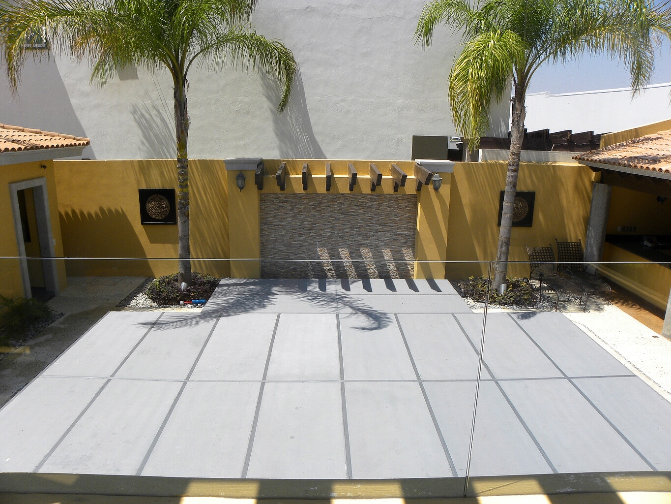Tarima blanca modular en patio hacienda con paredes amarillas, palmeras y decoración tropical profesional