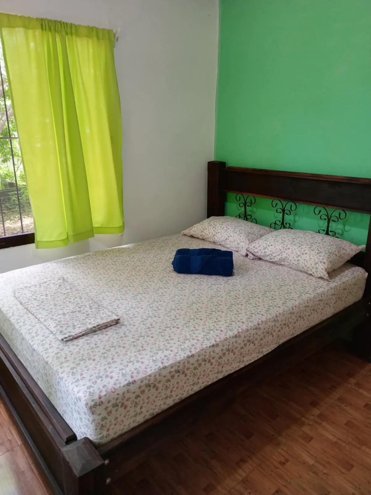 Cama doble con ropa de cama clara en un dormitorio verde